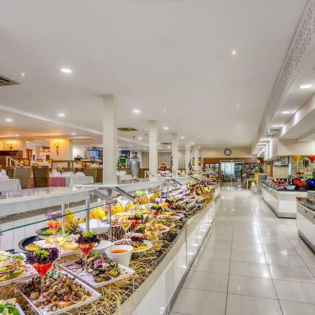 Sealife Family Resort Hotel Antalya Exterior photo The photo shows a spacious dining area, likely a buffet or restaurant, featuring a wide array of colorful food presentations. There are multiple serving stations with neatly arranged dishes, including a variety of salads, appetizers, and desserts. Th