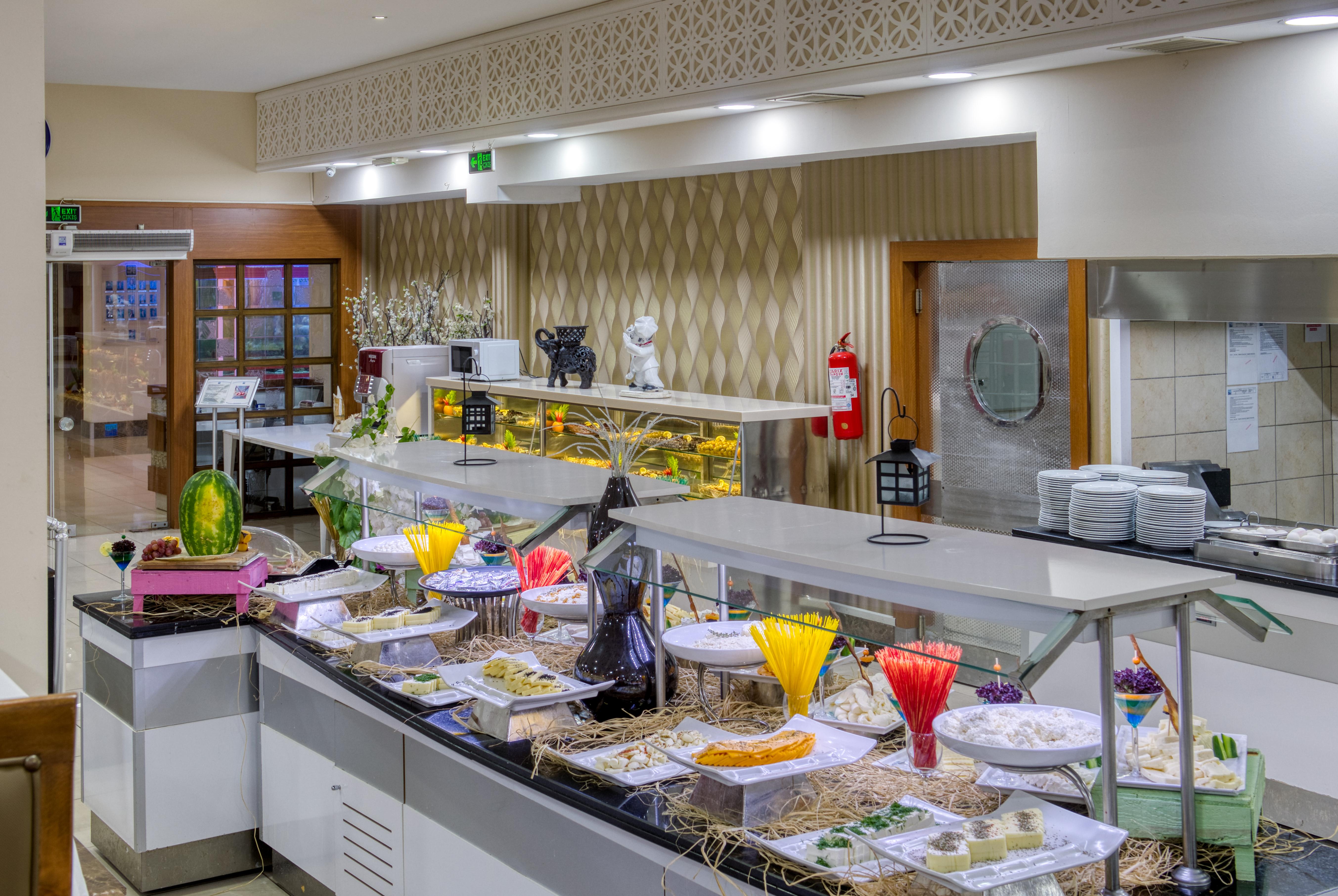 Sealife Family Resort Hotel Antalya Exterior photo The image shows a buffet or dining area featuring a variety of colorful dishes and desserts displayed on a long serving counter. It includes decorative plates and containers filled with food items, likely intended for a buffet setup. The overall envi