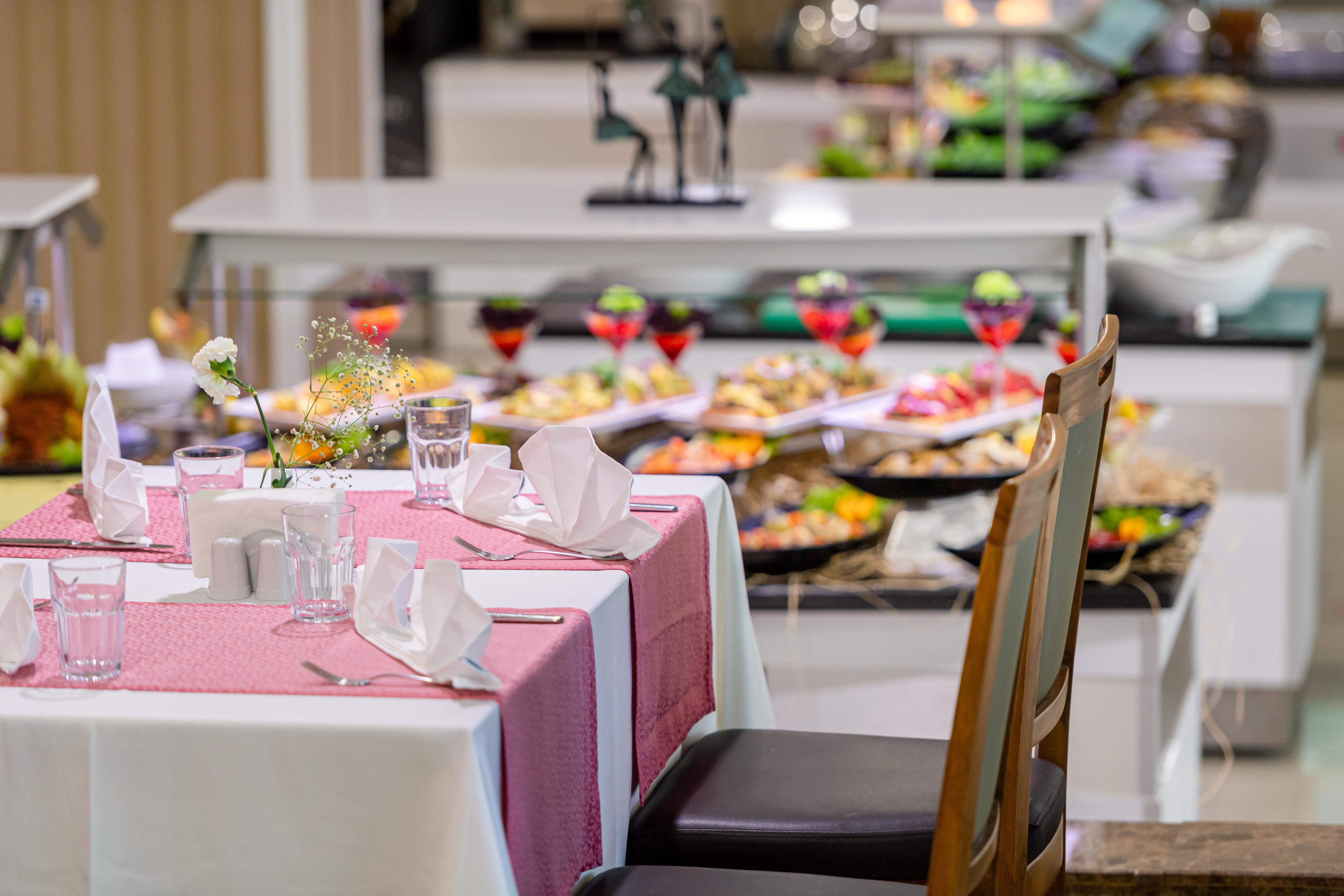 Sealife Family Resort Hotel Antalya Exterior photo The photo features a dining area of a buffet restaurant. In the foreground, there's a neatly set table with a pink tablecloth, white napkins, and glasses. In the background, a variety of dishes is displayed on a buffet table, showcasing an assortment