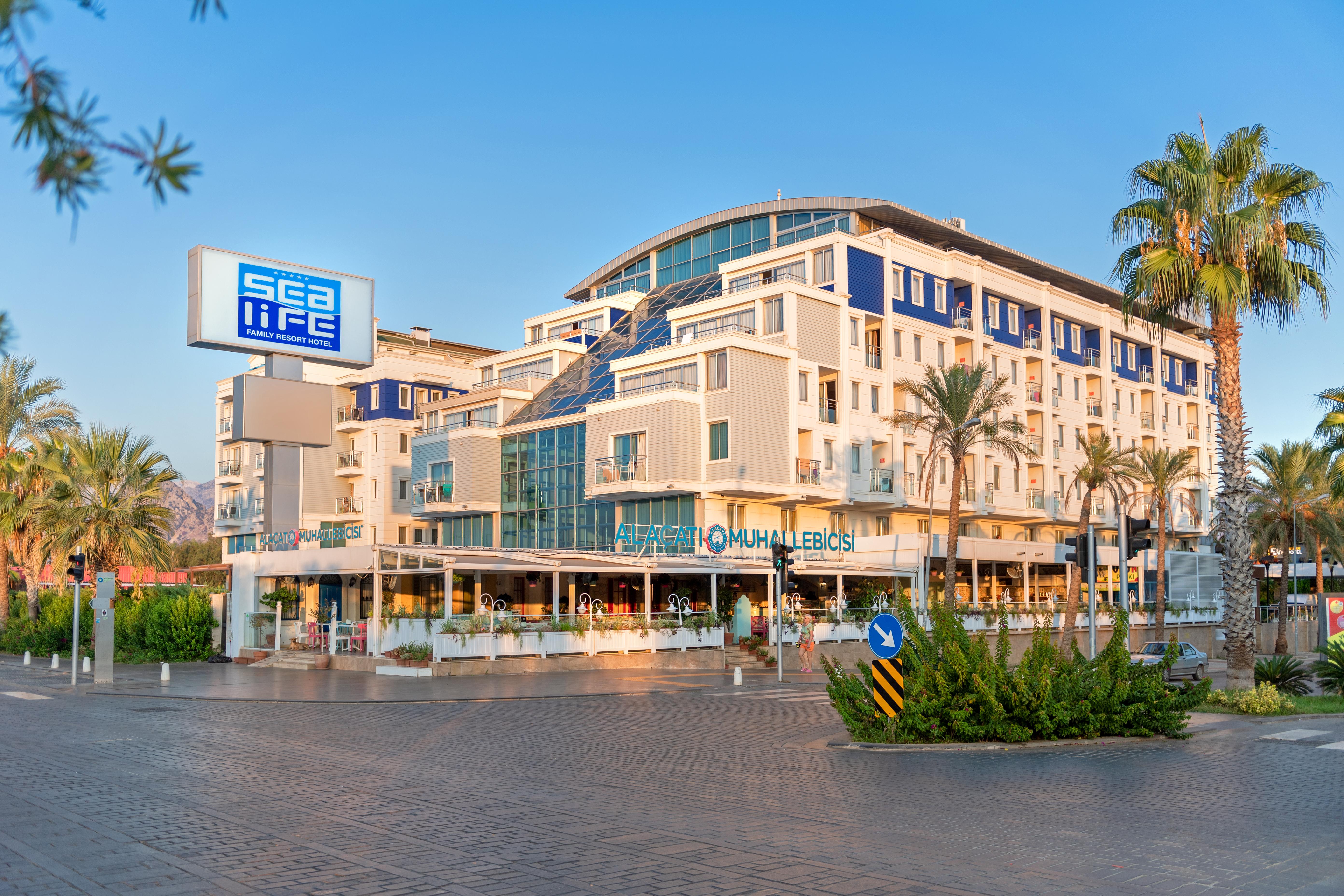 Sealife Family Resort Hotel Antalya Exterior photo The photo shows a modern building with a contemporary architectural design, featuring multiple levels and large glass windows. There is a sign that reads "sea life" prominently displayed on the left. The building appears to house a restaurant or café