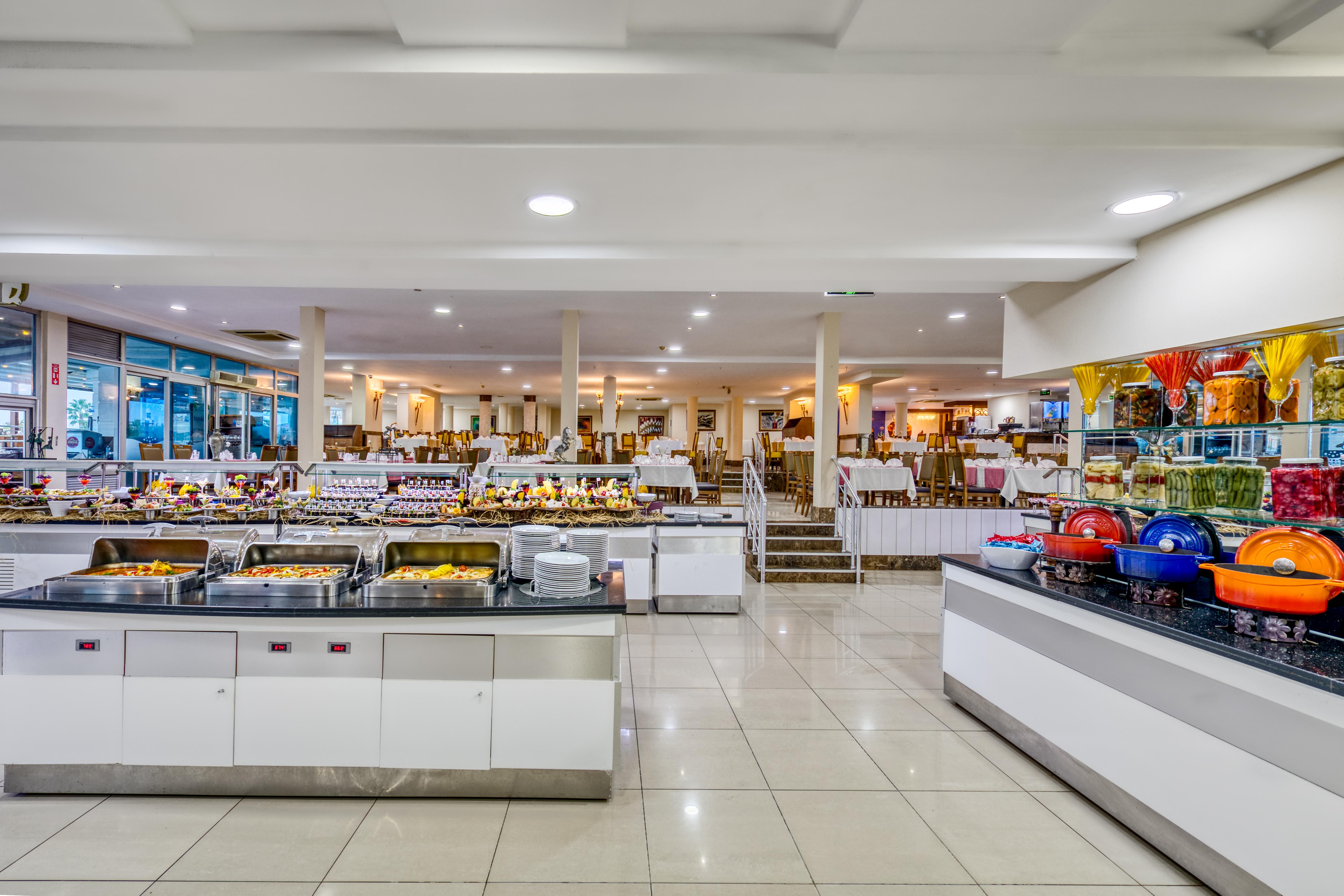 Sealife Family Resort Hotel Antalya Exterior photo The photo depicts a spacious buffet dining area featuring several food stations. There are multiple serving counters filled with a variety of dishes, showcasing an array of foods typically found in a buffet setting. The space is well-lit, with a mode