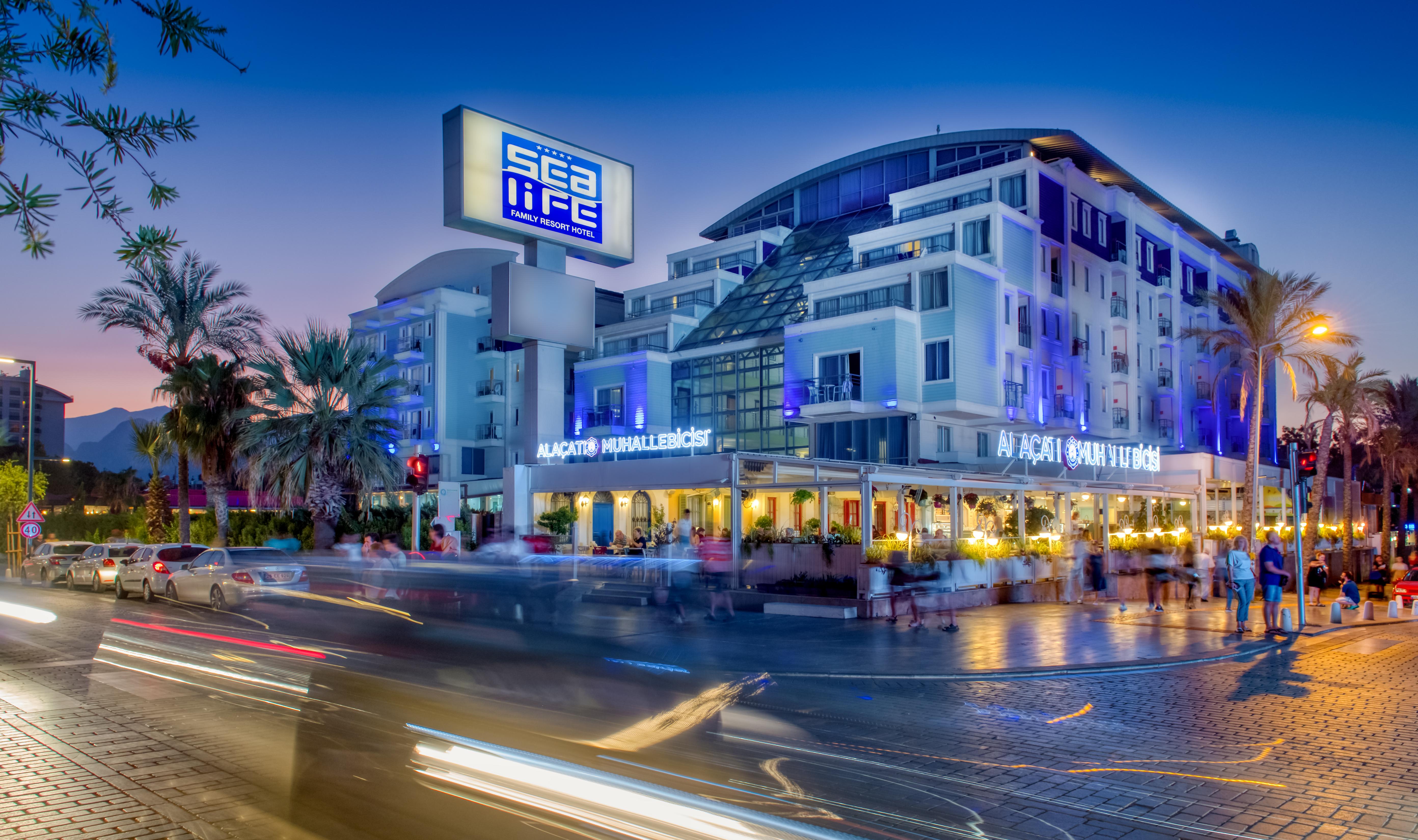 Sealife Family Resort Hotel Antalya Exterior photo The photo shows a modern building with a prominent sign that reads "Sea Life." The structure has multiple stories and a sleek, contemporary design, featuring large windows. In front of the building, there appears to be a restaurant with outdoor seati