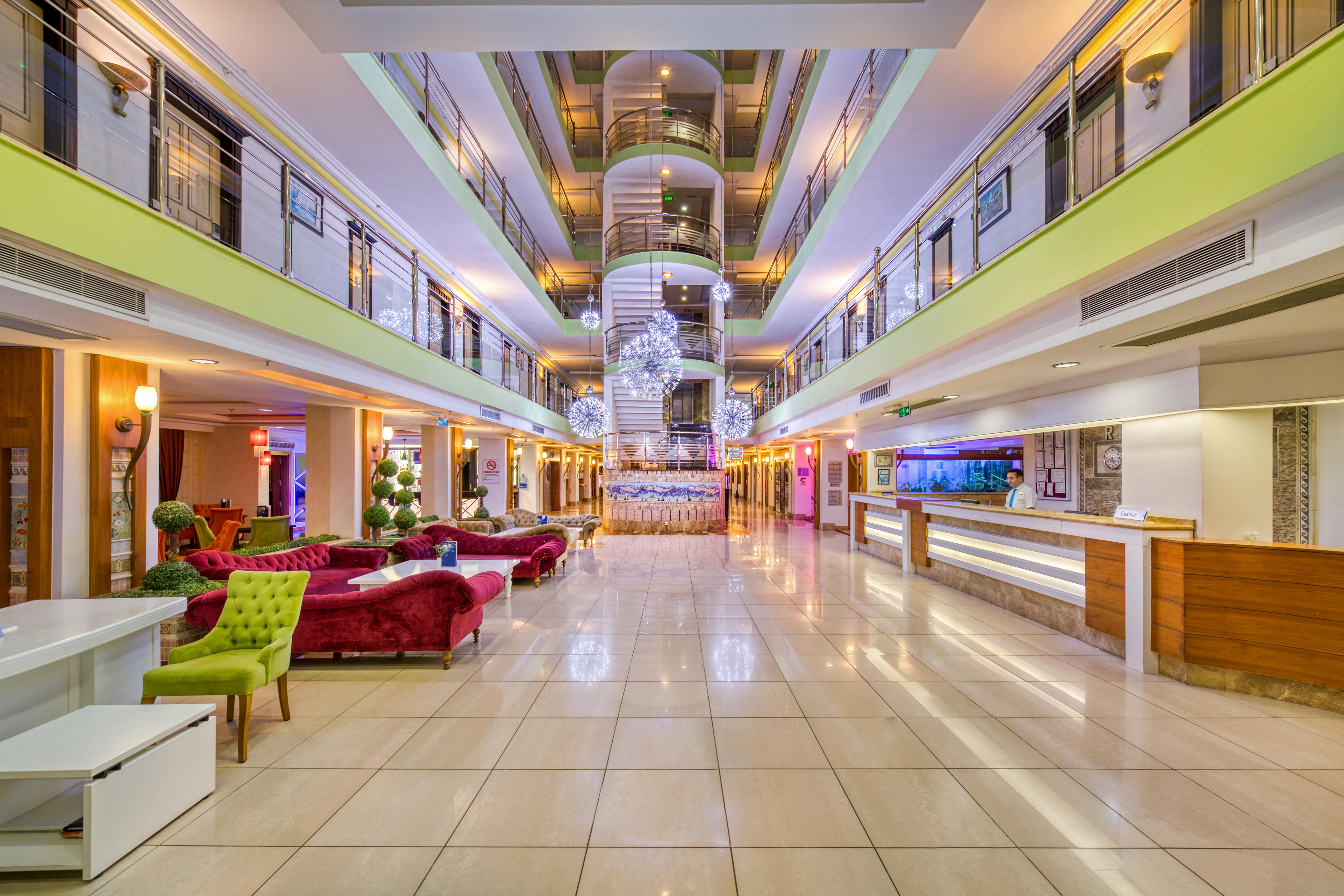 Sealife Family Resort Hotel Antalya Exterior photo The photo shows the interior of a modern hotel lobby. It features a spacious design with a polished tile floor and various seating areas. Elegant sofas in vibrant colors, such as red and green, are arranged tastefully. In the center, there is a strik