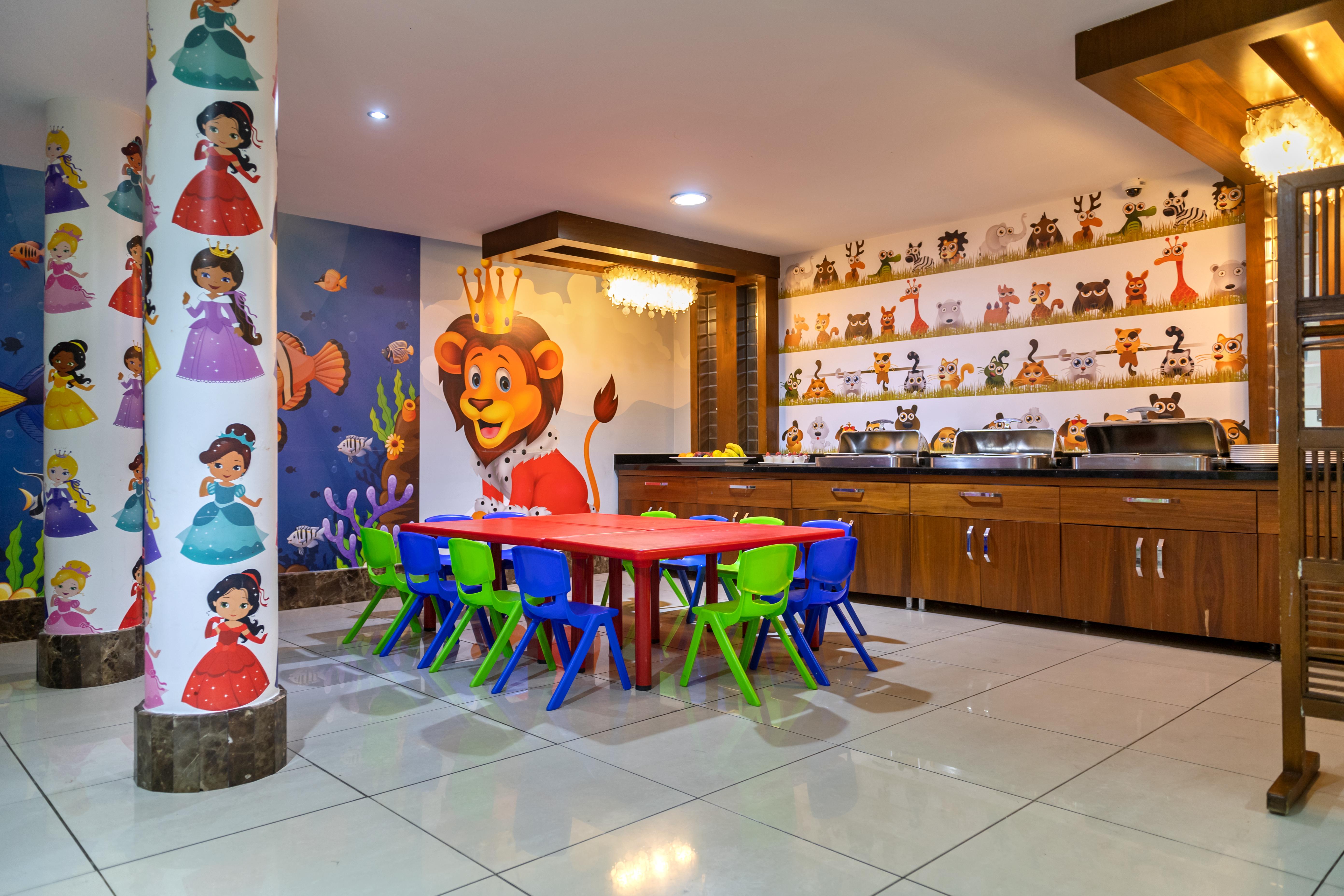 Sealife Family Resort Hotel Antalya Exterior photo The photo shows a vibrant children's playroom or activity area. There is a red table surrounded by small chairs in various colors (blue and green). The walls are decorated with colorful murals, including images of cartoon characters, animals, and pri