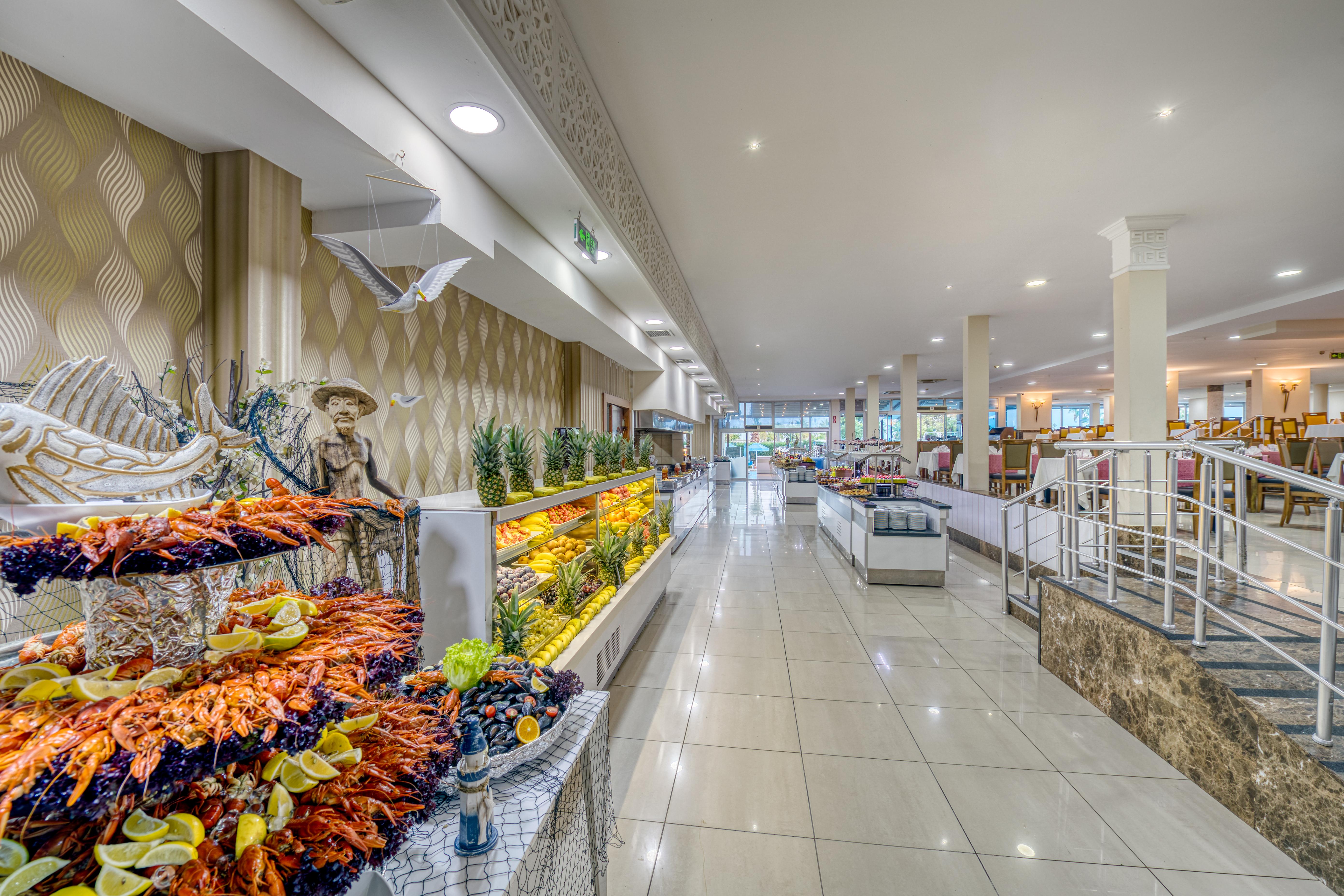 Sealife Family Resort Hotel Antalya Exterior photo The photo shows the interior of a spacious dining area, likely in a restaurant or buffet. The space features a long corridor with glossy tiled floors and bright, well-distributed lighting. On one side, there are decorative displays of seafood, includ