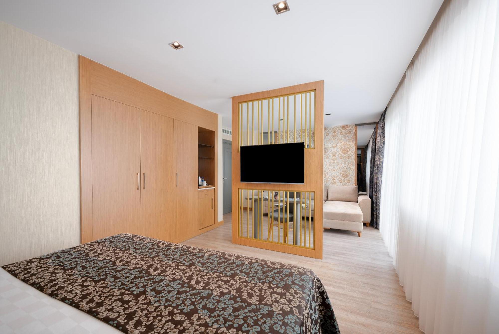 Sealife Family Resort Hotel Antalya Room photo The photo depicts a modern hotel room designed with a clean and minimalistic aesthetic. It features a spacious layout with wooden flooring and a combination of light and dark colors. 

On one side, there is a bed with a patterned dark bedspread. The 