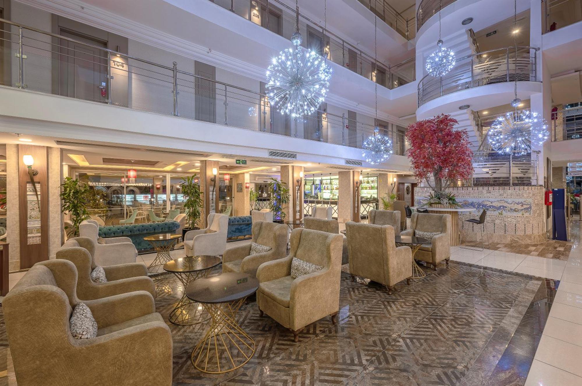 Sealife Family Resort Hotel Antalya Exterior photo The photo depicts a modern hotel lobby with a stylish and inviting atmosphere. It features a seating area furnished with plush, beige armchairs arranged around a round glass table. The floor boasts an elegant patterned design. 

In the background, th