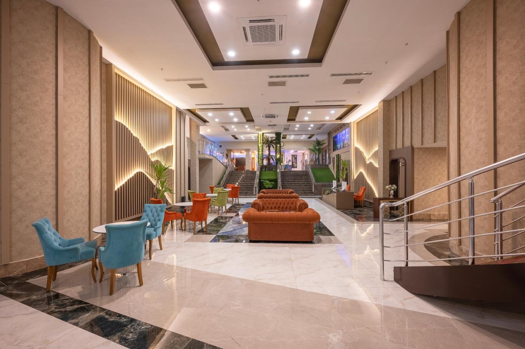 Sealife Family Resort Hotel Antalya Exterior photo The photo shows a modern lobby area of a hotel or building. The space is spacious, featuring a mix of lighting and decorative elements. There are elegant furnishings, including an orange sofa and colorful chairs in blue and orange. The floor is made 